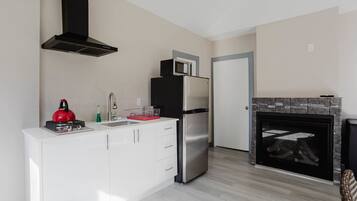 Een koelkast, een magnetron, een kookplaat, kookgerei, borden en bestek