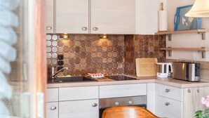 A modern kitchen with a hexagonal tile backsplash, stainless steel appliances, and light wood cabinetry.