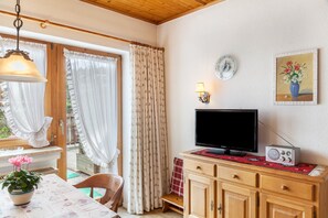 A room with a television, radio, and a clock on the wall.