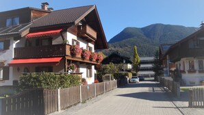 A street with traditional wooden houses, a paved road, and a mountain in the background.