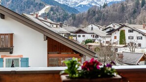 A residential area with houses, a wooden balcony, and a mountain backdrop. - Apartment 'Wank' with Mountain View, Balcony and Wi-Fi (Garmisch-Partenkirchen)