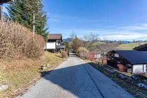 Une route de campagne menant à des maisons, avec un ciel dégagé.