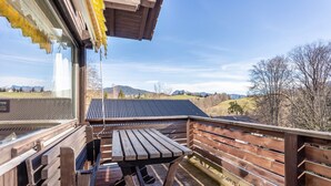 Una terrassa de fusta amb una taula de pícnic i vista a un paisatge de muntanya.