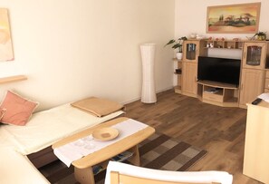 Ein gemütlicher Raum mit Bett, kleinem Tisch, Fernseher und Schrank.