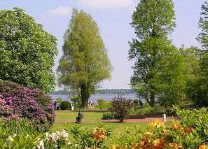 A garden with a statue, a lake view, and a clear sky. - Apartment 'Ferienwohnung  Zum Rosenteich' with Balcony and Wi-Fi (Bad Zwischenahn)