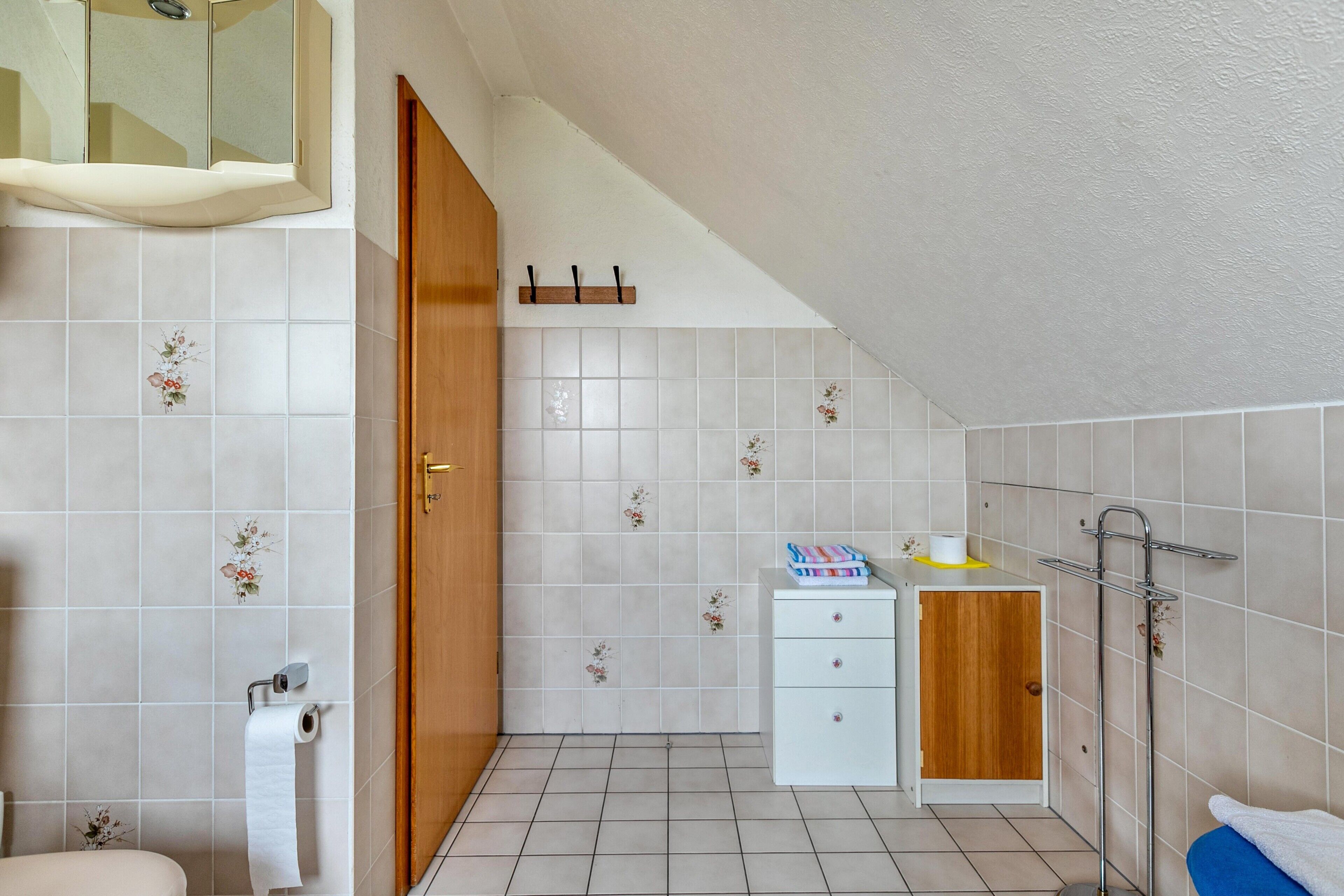 A small bathroom with a toilet, a sink, a mirror, a towel rack, and a cabinet.