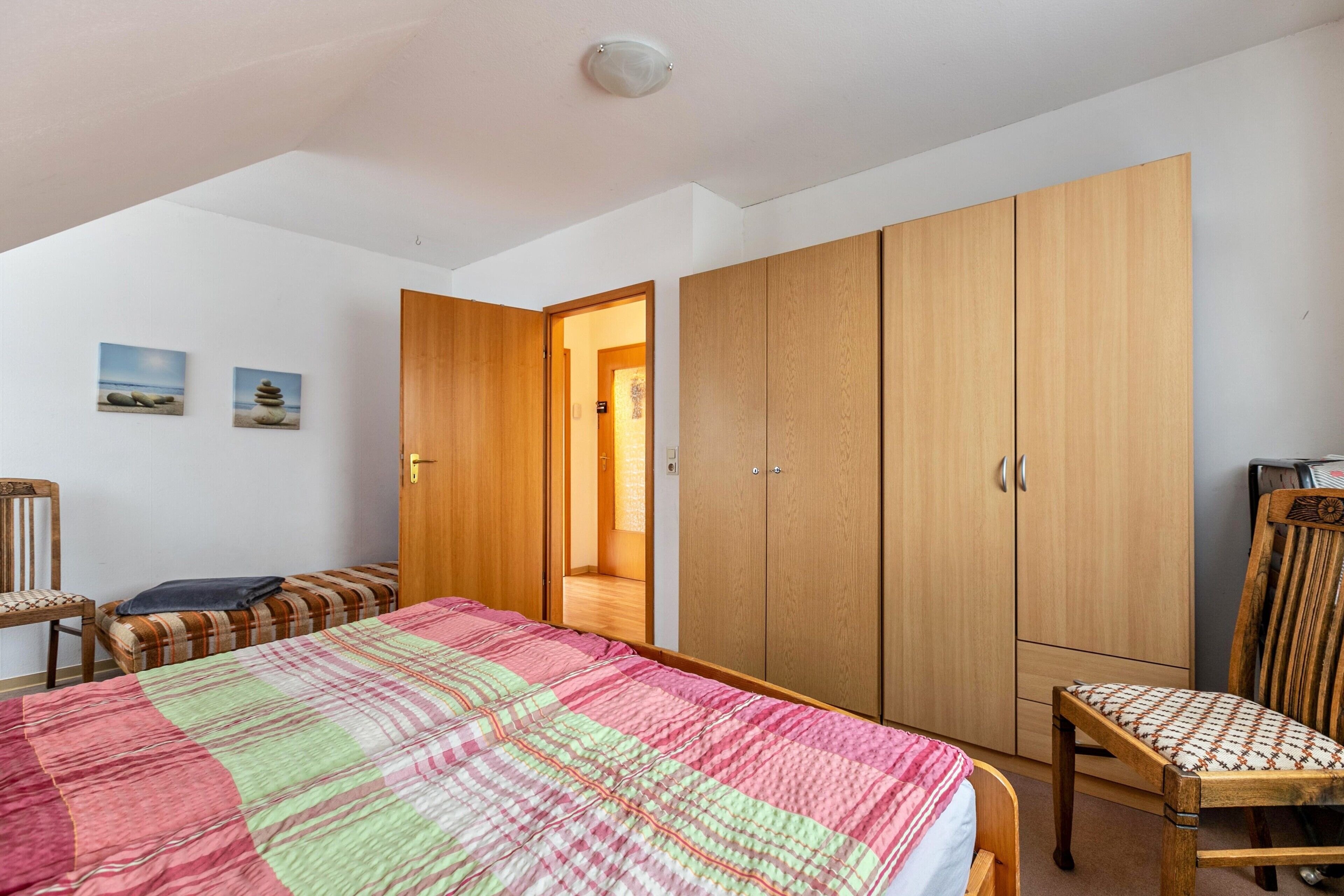 Une chambre à coucher avec un lit, une armoire en bois, une chaise et un banc.