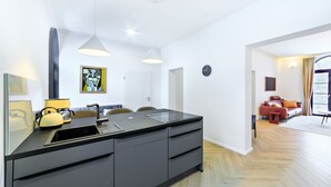 A modern kitchen with a central island, pendant lighting, and a view into the living area. - Holiday Apartment "Schlossplatz Vogtland" with Private Terrace, Private Sauna & Wi-Fi (Auerbach)
