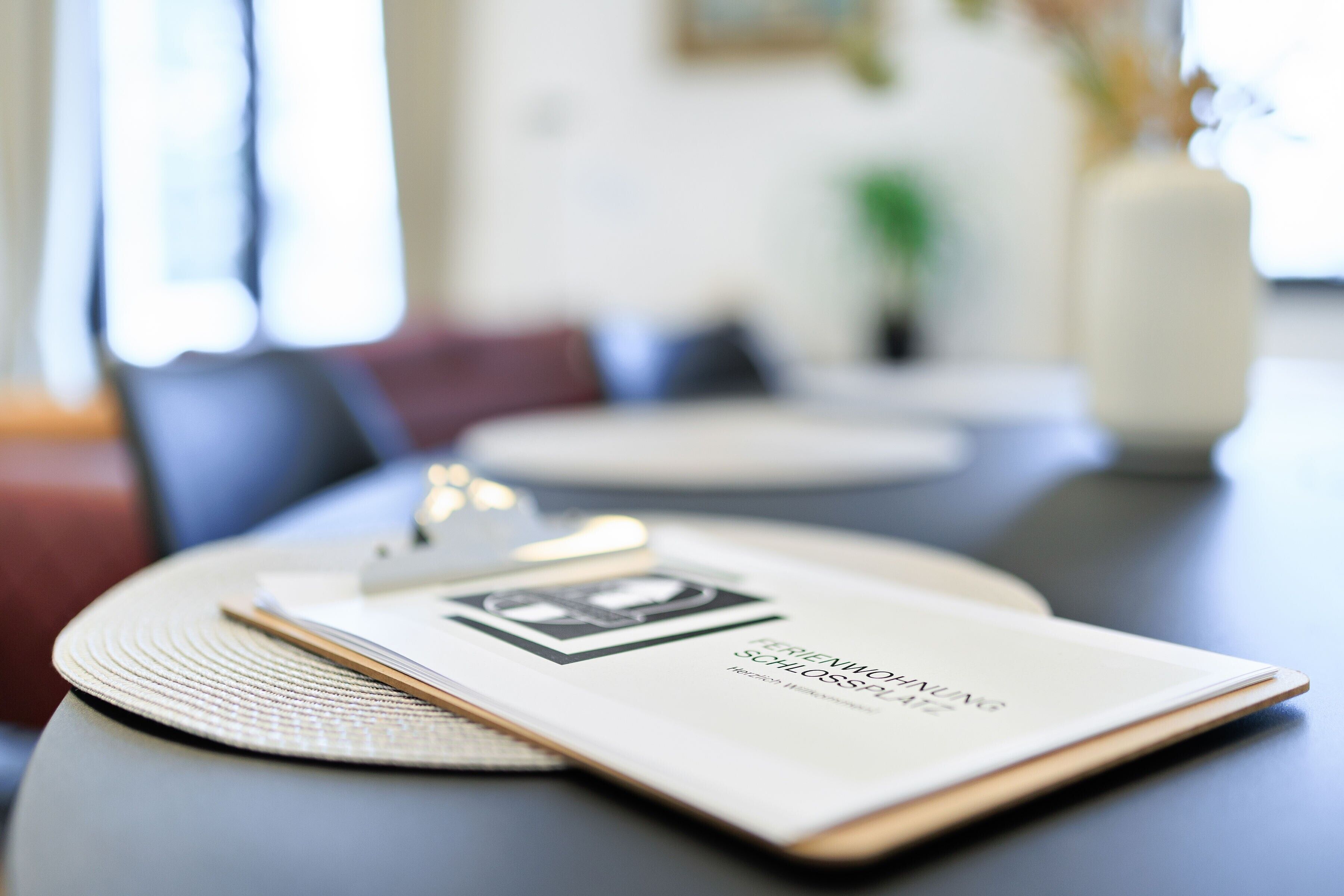 Een boek met de titel 'FASHION IN THE 21st CENTURY' op een tafel met een placemat.