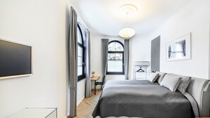 A modern hotel room with a large bed, a desk, a chair, and a TV. - Holiday Apartment "Schlossplatz Vogtland" with Private Terrace, Private Sauna & Wi-Fi (Auerbach)