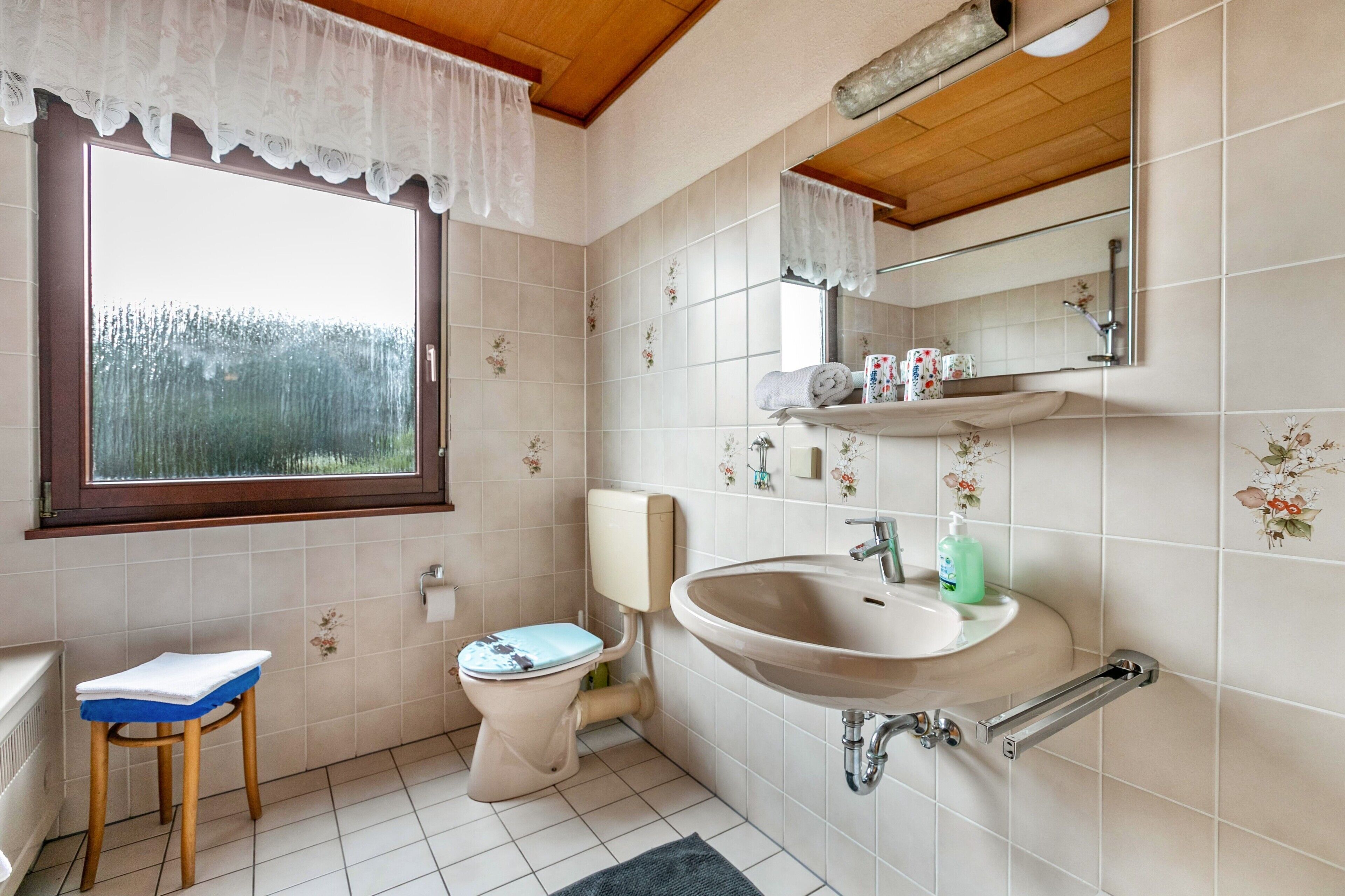 A bathroom with a toilet, sink, and window.