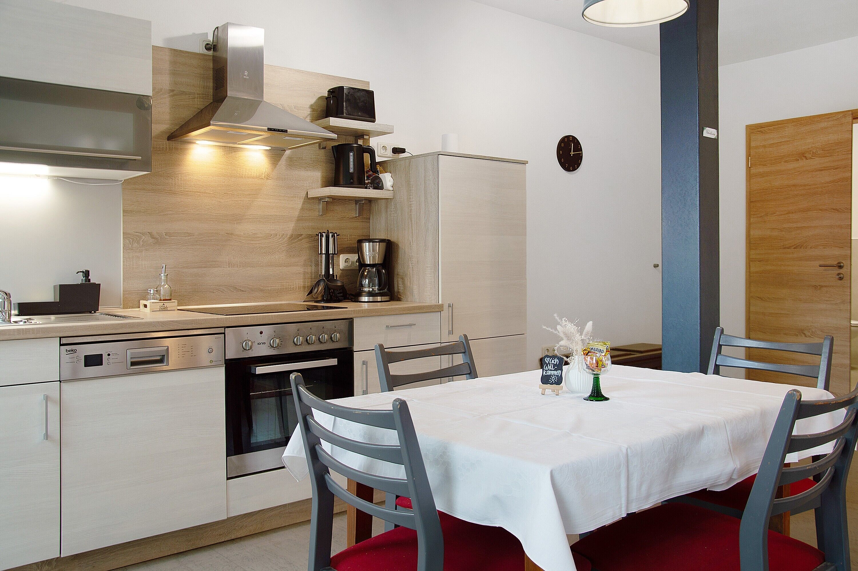 A modern kitchen with a dining area, stainless steel appliances, and a wooden accent wall.