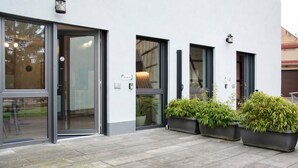Un edifici amb grans portes de vidre, plantes en testos i un disseny net i modern.