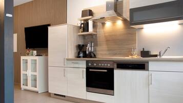 A modern kitchen with built-in appliances, a wooden accent wall, and a flat-screen TV.