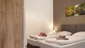 Habitació d'hotel amb dos llits, una paret de fusta, un quadre i una tauleta de nit amb una làmpada.