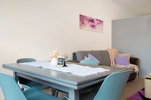 A dining area with a table, chairs, a placemat, a vase with dried flowers, and a small chalkboard sign. - Apartment 'Kornblume' with Private Terrace, Shared Garden and Wi-Fi (Wittighausen)