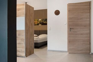 A bedroom with a bed, a wall-mounted clock, and a wooden door. - Apartment 'Kornblume' with Private Terrace, Shared Garden and Wi-Fi (Wittighausen)