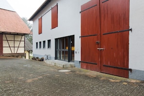 A building with large red doors, a white exterior, and a tiled ground.