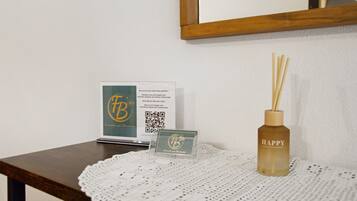 Un tavolo di legno con un codice QR, un bigliettino e una bottiglia di diffusore di fragranze.