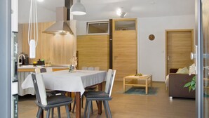 Een moderne eetruimte met een tafel voor vier personen, een keuken op de achtergrond en een bank in de woonkamer.