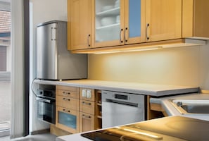 Une cuisine moderne dotée d’appareils électroménagers en acier inoxydable, de meubles en bois et d’un lave-vaisselle encastré.