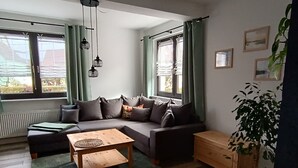 A living room with a sofa, a coffee table, a potted plant, and a radiator. - Apartment 'Papperitz' with Mountain View, Private Terrace and Wi-Fi (Uhlstädt-Kirchhasel)