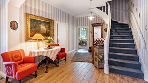 A room with a dining table, chairs, a staircase, and a painting on the wall. - Apartment 'Ferienwohnung Bauernhof Rohde' with Shared Terrace, Private Garden and Wi-Fi (Gremersdorf)