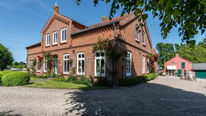 A large brick house with multiple windows and a gravel driveway. - Apartment 'Ferienwohnung Bauernhof Rohde' with Shared Terrace, Private Garden and Wi-Fi (Gremersdorf)