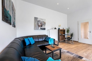 Ein modernes Wohnzimmer mit einem Ecksofa, einem Couchtisch, einer Stehlampe und einem Bild an der Wand.