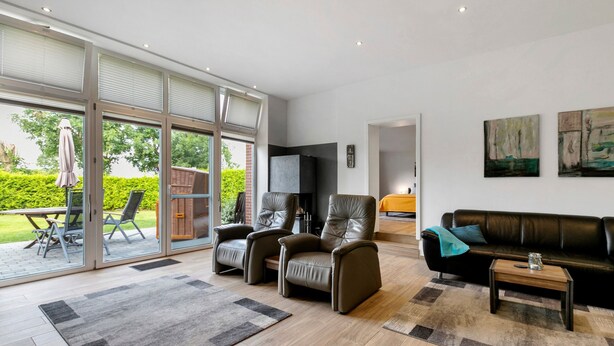 Un salon moderne comprenant un canapé, des fauteuils, une table basse et un téléviseur.