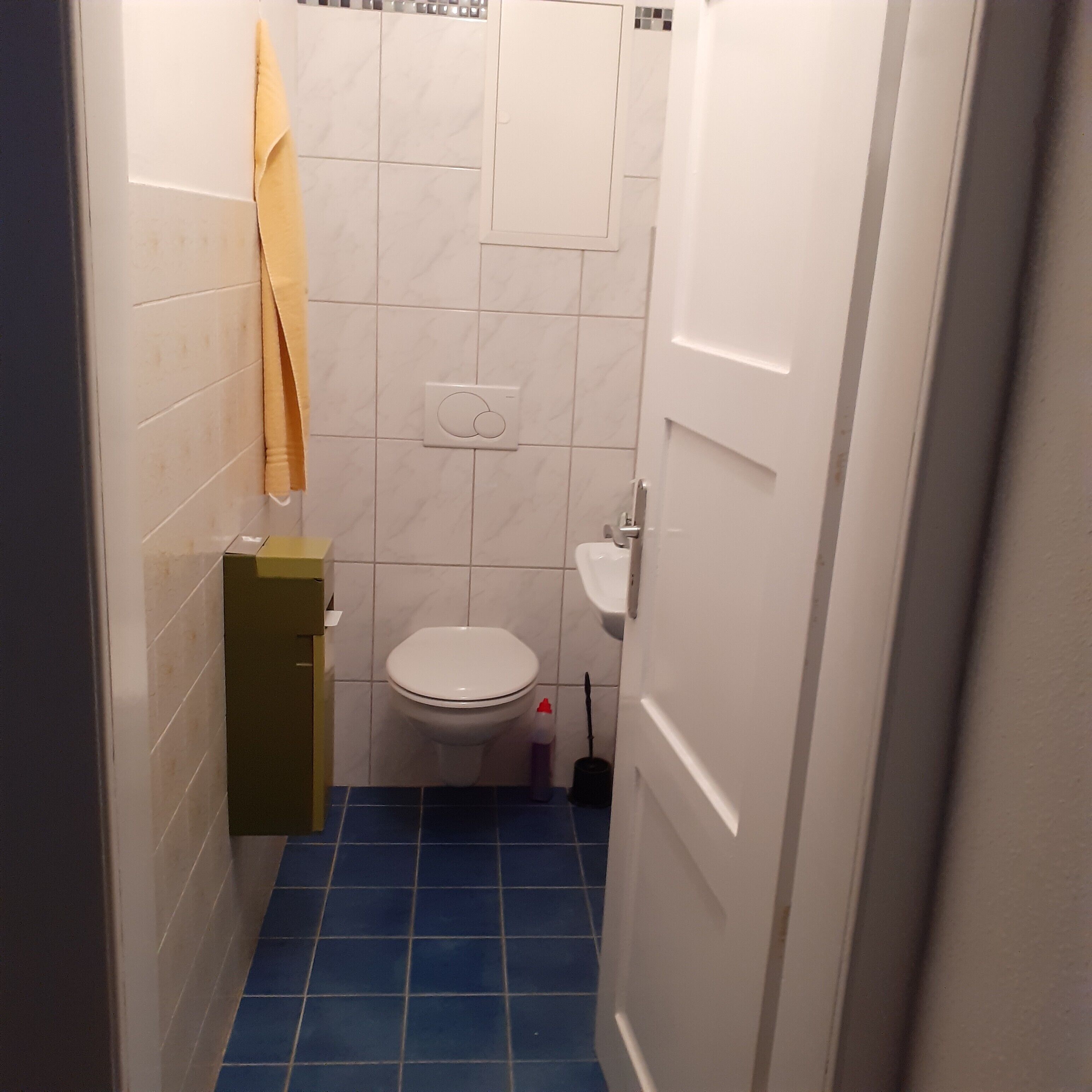 A small bathroom with a toilet, a sink, and a blue-tiled floor.