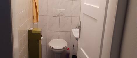 A small bathroom with a toilet, a sink, and a blue-tiled floor.