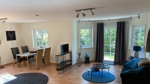 Una sala de estar con comedor, televisor, sofá y mesa de centro.