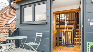 A modern building with a balcony, a table and chairs, and a staircase leading to an upper level. - Apartment 'St Georgen 1' with Shared Terrace, Balcony and Wi-Fi (Freiburg im Breisgau)