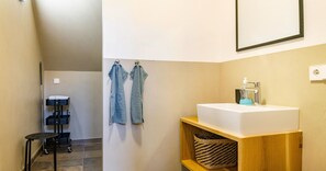 A bathroom with a white sink, a wooden shelf, a towel rack with two towels, and a black cart with a white towel. - Apartment 'St Georgen 1' with Shared Terrace, Balcony and Wi-Fi (Freiburg im Breisgau)