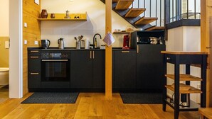 A modern kitchen with black cabinets, wooden flooring, and a built-in oven. - Apartment 'St Georgen 1' with Shared Terrace, Balcony and Wi-Fi (Freiburg im Breisgau)
