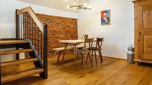 A room with a wooden staircase, a brick wall, a dining table with chairs, and a wooden cabinet. - Apartment 'St Georgen 1' with Shared Terrace, Balcony and Wi-Fi (Freiburg im Breisgau)