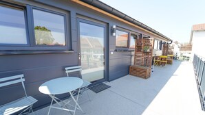 A modern building with large windows, a balcony with outdoor furniture, and a door with a window. - Apartment 'Wendlingen 3' with Shared Terrace, Balcony and Wi-Fi (Freiburg im Breisgau)
