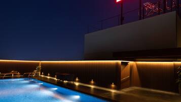 A swimming pool with a modern design, a neon sign, and a well-lit area with seating.