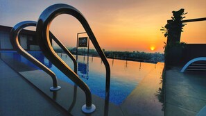 A rooftop pool with a sunset view, metal railings, and a sign for 'LOYO by TOMORROW'. - Luxo Kochi (Kanayannur)