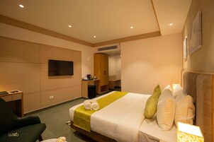 Una habitación de hotel moderna con una cama grande, un escritorio, una silla y un televisor de pantalla plana montado en la pared.