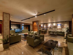 A modern living room with sofas, a coffee table, and a TV. There are framed pictures on the wall and a plant on the floor. - Luxo Kochi (Kanayannur)