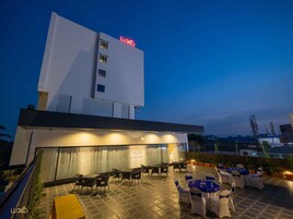 Exterior moderno de un hotel con un patio en la azotea, zona de estar al aire libre y vistas al rótulo del edificio.