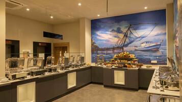 Un espace buffet agrémenté d’une fresque murale sur le thème de la mer, de distributeurs de boissons en verre transparent et offrant une grande variété de plats.