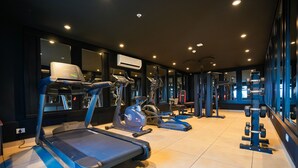 Une salle de sport équipée de tapis de course, de vélos elliptiques et de matériel de musculation.