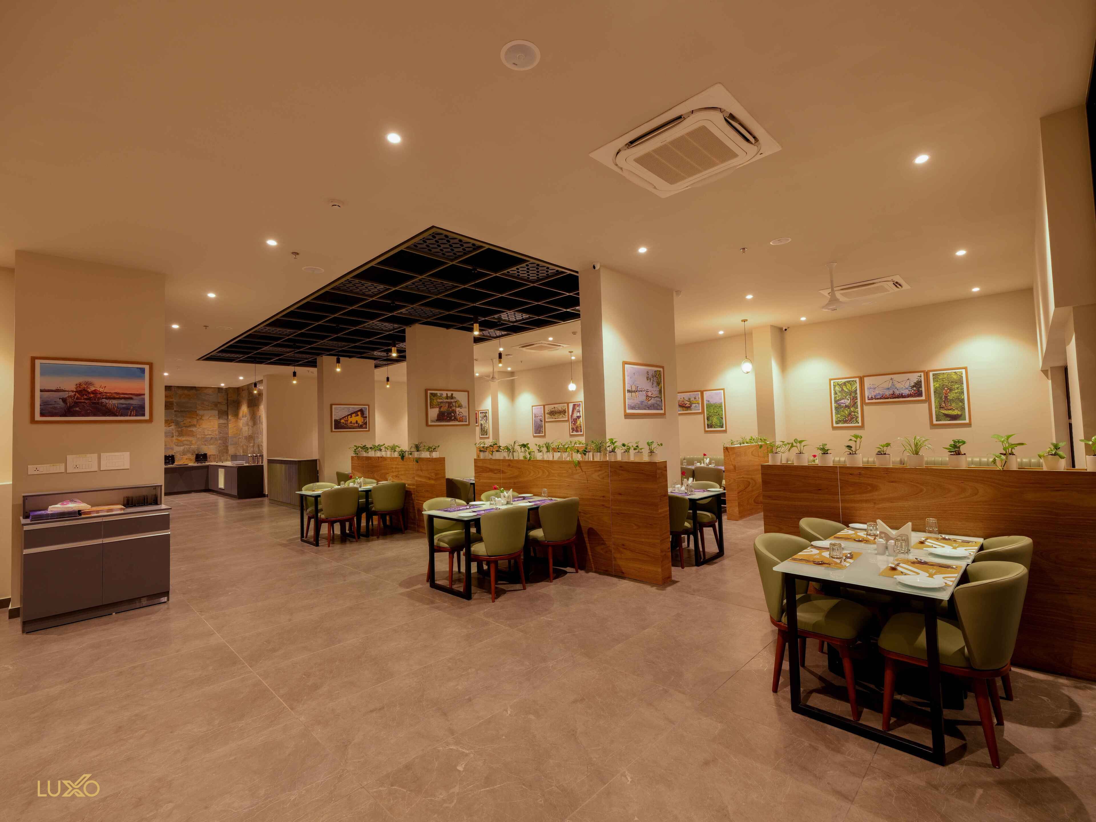 Een restaurant met een modern interieur, met houten scheidingswanden, groene stoelen en diverse ingelijste foto's aan de muren.