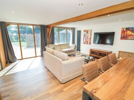 Un salón espacioso con un sofá grande, una mesa de comedor de madera y un televisor.