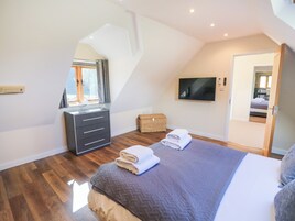 Un dormitorio con cama, cómoda, televisor y ventana con cortinas.