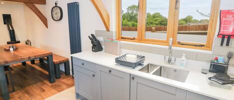 Une cuisine moderne avec une grande fenêtre, une table à manger en bois et un tapis coloré.
