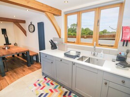 Una cocina moderna con un ventanal grande, una mesa de comedor de madera y una alfombra colorida.